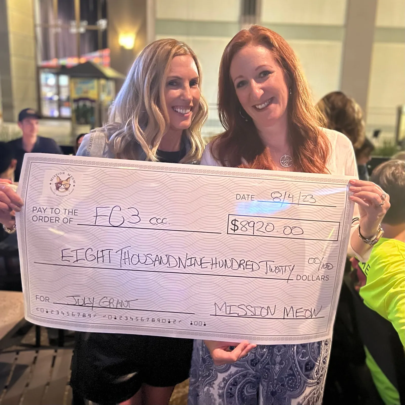 Two women hold a giant $8,920 check made out to FC3, the Firelands Community Cat Coalition