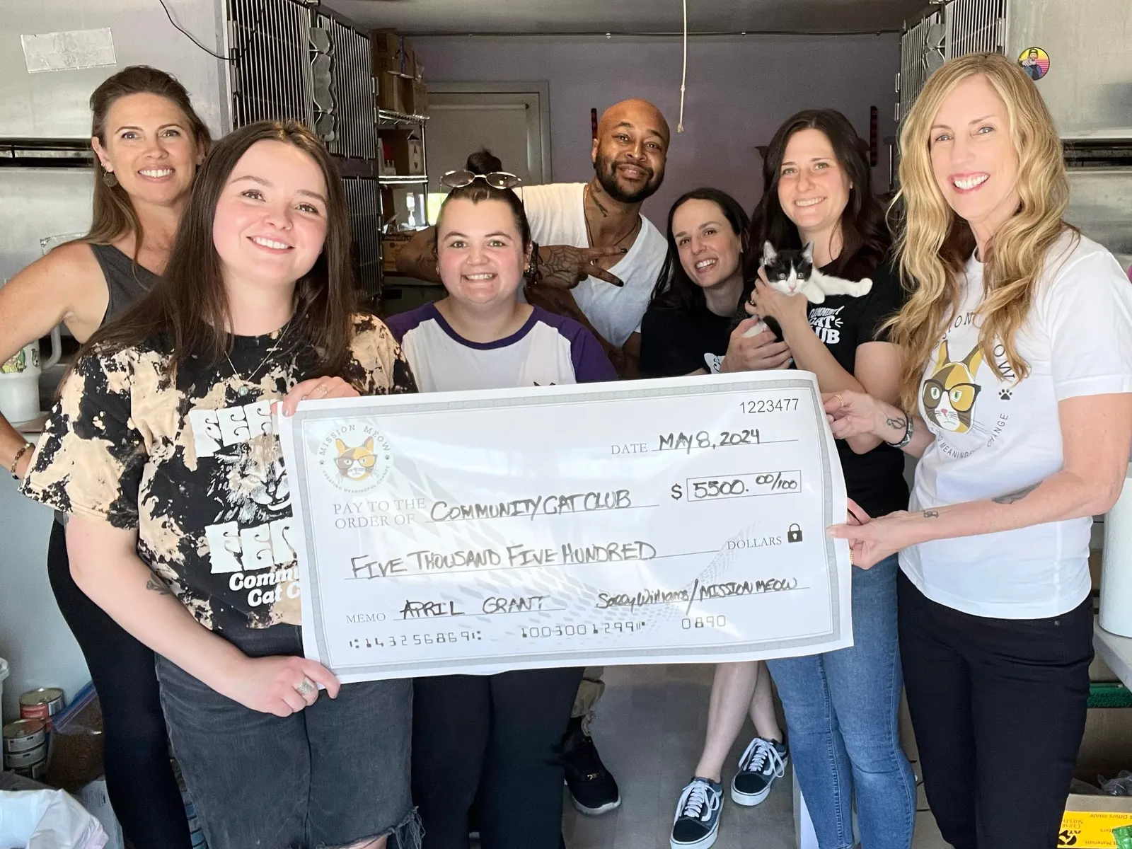 The Community Cat Club team and Sally hold a $5,500 Mission Meow check in their cat room