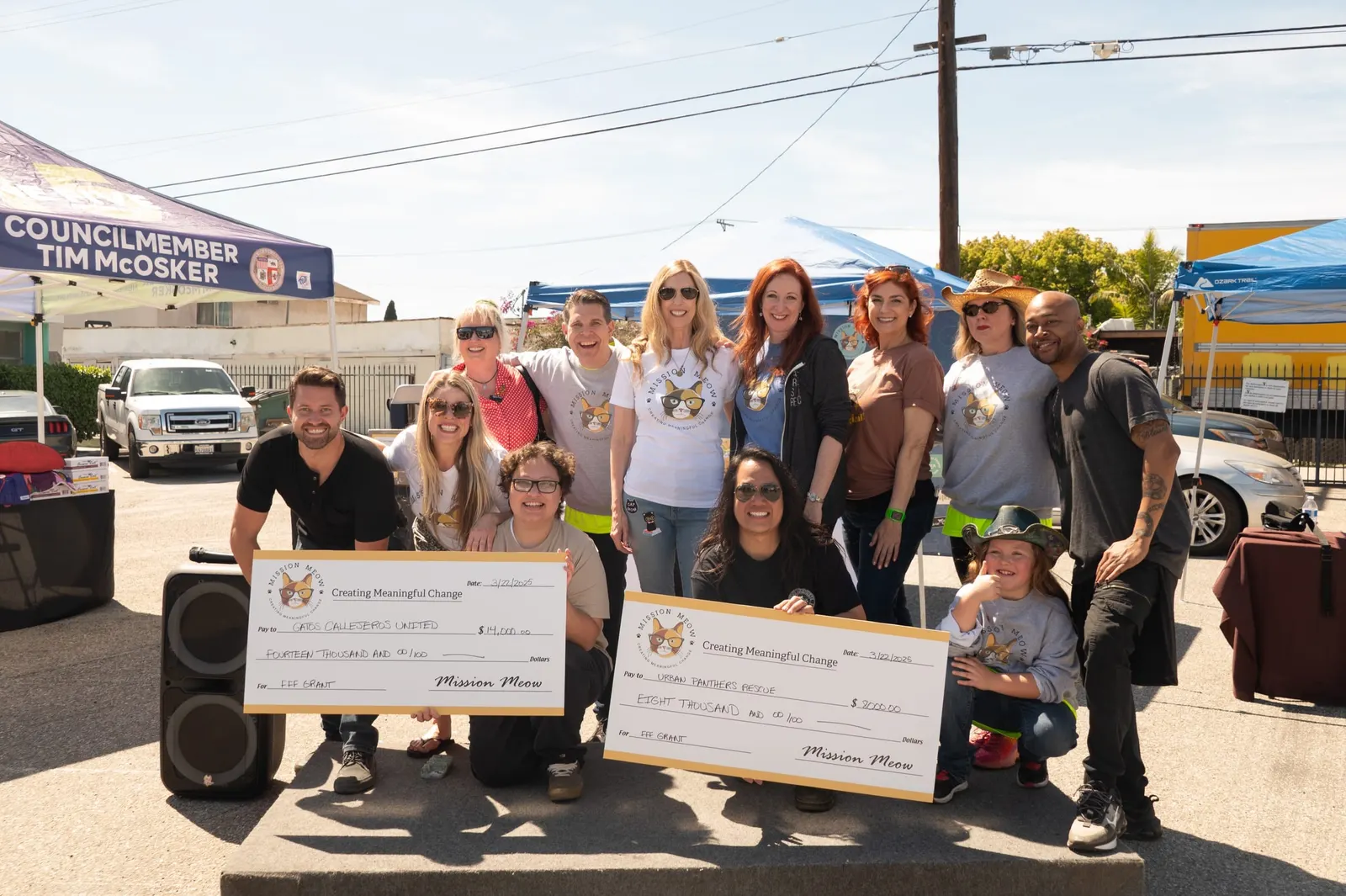 A group in Mission Meow T-shirts gathers behind the $14,000 Gatos Callejeros United and $8,000 Urban Panthers Rescue Feline Fix Fest checks