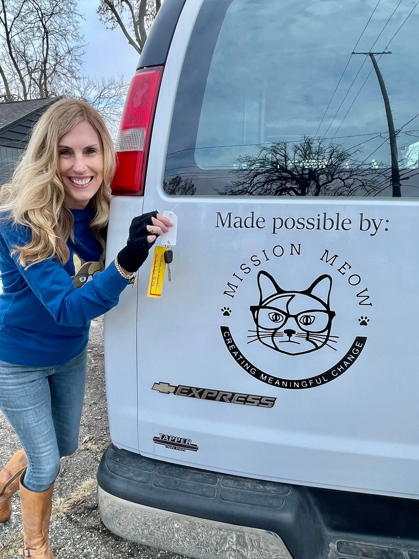 A smiling woman beside a white transport van with a “Made possible by: Mission Meow” decal