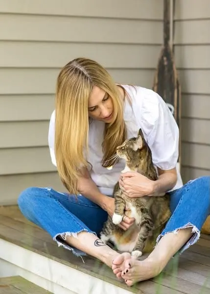 Sally Williams sitting barefoot on a porch step with Marlin in her lap